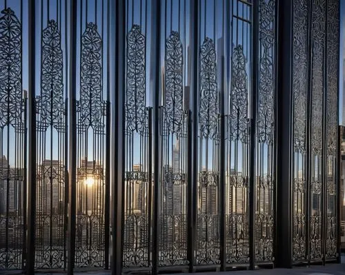 Modern architectural fence, ornate metal design, intricate patterns, silver-gray finish, vertical bars, symmetrical composition, urban setting, cityscape, skyscrapers in background, morning sunlight, 