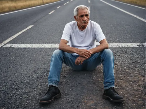 An old man wearing a white t-shirt and jeans sitting on the side of the road near a crossroads, sadness, loneliness, crying, cloudy sky, open plan image, no way , end of life,roadside,man portraits,ro