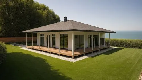 small modern house surrounded by a garden.
The walls are white. Dark roof. There is a lawn around the house.,a small white house with open glass windows in a field,summerhouse,summer house,dunes house