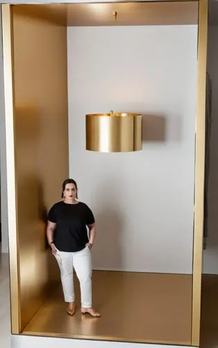 a powder room, with a gold chandelier in the middle of the room, a young woman in the middle of the powder room,a woman standing in a room with gold walls,stav,kafeel,greek in a circle,choksi,spherion