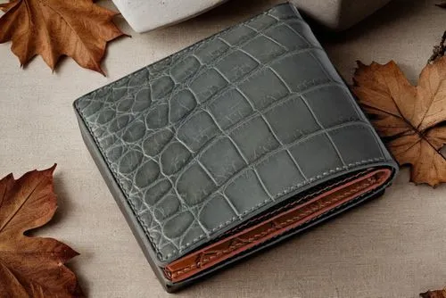 a leather wallet sitting on top of leaves,wallet,smythson,wallets,crocodile skin,cardholder,leather goods