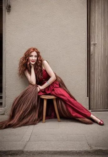 the photography depicts a captivating woman with long, flowing chestnut hair and a fiery red lips. Her long, brown curly hair is brought to life as she sits in a wooden chair in the middle of a bright