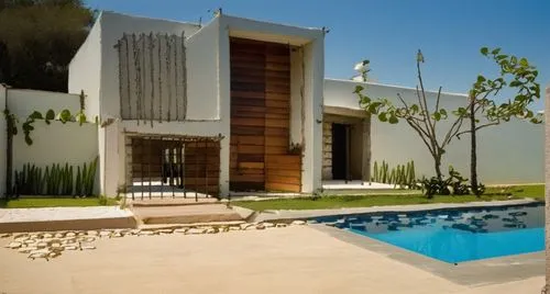 To the horizon, a sleek interior of a minimalistic house decorated with soft white concrete elements, and a weathered wooden access door. The house is surrounded by tranquil ponds and surrounded by lu