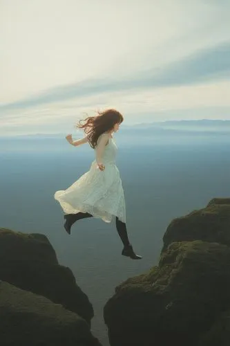 a woman with long red hair is in white dress flying through the air,flying girl,weightlessness,adrift,weightless,leap for joy,leap,floating in the air,little girl in wind,falling,freefall,volare,fairi