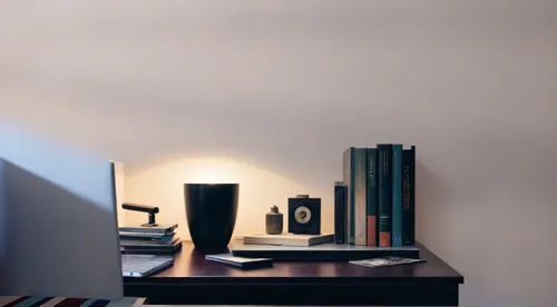 I want a small study desk with books, a lamp, and a computer,desk lamp,bedside lamp,blur office background,table lamp,table lamps,wall lamp,bookshelf,desk,nightstand,bookshelves,writing desk,office de