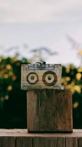 an old cassette tape is on top of a piece of wood,wooden birdhouse,reading owl,wooden cable reel,wooden figure,bird house,birdhouse