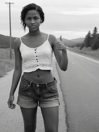 B&W high res photo: A poor-looking young woman stands at the side of the road with her thumb up, hitchhiking.,a young black woman posing for a po,hitchhikes,hitchhike,hitchhiking,monifa,lachanze,dibab