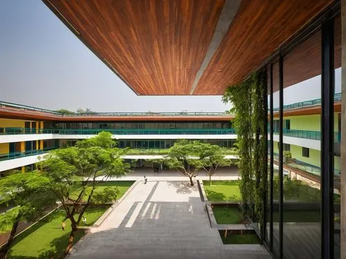 Pune, Aayojan School of Architecture and Design, modern building, glass facade, steel structure, white walls, green roofs, wooden accents, open courtyard, stairs, columns, arches, Indian architectural