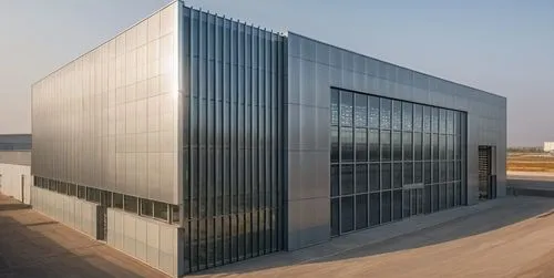 Describe a modern factory building . The façade of the factory combines perforated metal sheets with glass curtain walls, enhancing the aesthetic appeal of the industrial environment.,glass facade,met