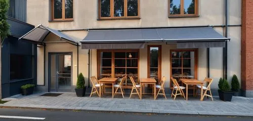 Facade of bakery. Walls color dark, terracotta. Glazing frames dark gray. Above the windows fabric awnings dark gray color. Lights are on in the windows and you can see the bread and baked goods insid