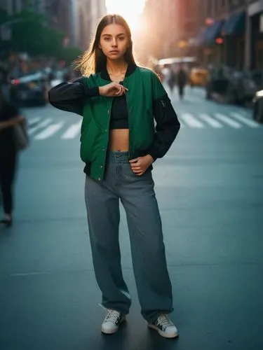 A young girl with long brown hair in sneakers walks through the busy streets of New York. In her green bomber jacket with black sleeves, which fastens with buttons, a lonely girl with a backpack on he