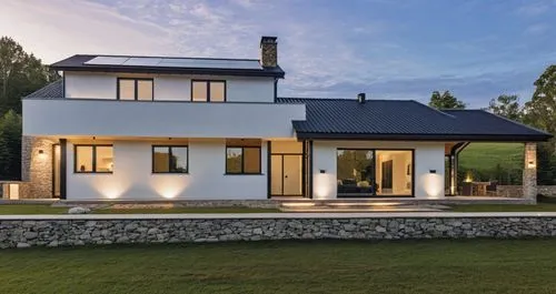 A minimalist Scandinavian-style house with a gable roof, featuring large windows with black frames and stone details on the facade. The house has a sleek glass balcony, adding a modern touch to the de