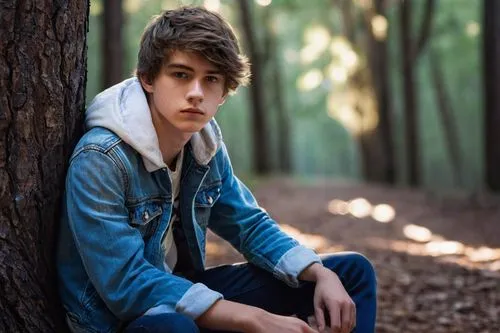 Ash Morgenstern, teenage boy, 17yo, blue eyes, messy brown hair, casual wear, denim jacket, white t-shirt, ripped jeans, sneakers, backpack, sitting, leaning against a tree, forest, afternoon sun, war