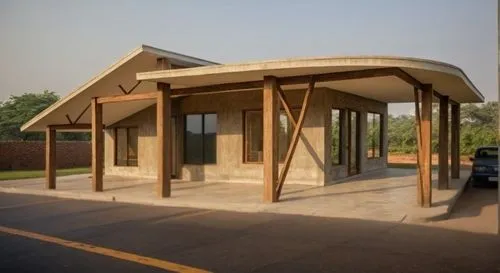 a very small, concrete structure that is standing next to a street,bus shelters,carports,folding roof,carport,visitor center,bus stop