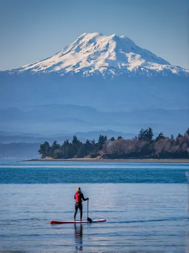 A SUP paddleboarder heads in to shore at Cline Spit in Sequim, WA on a cold day. Mt. Baker can be seen in the distance.,standup paddleboarding,stand up paddle surfing,llanquihue lake,paddleboard,paddl