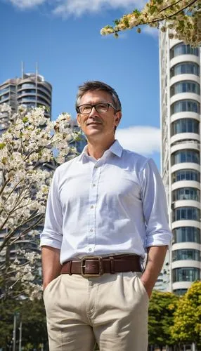 Middle-aged, male, architectural designer, Tauranga, standing, confident pose, glasses, short brown hair, casual clothing, white shirt, dark blue pants, brown leather belt, holding a large blueprint, 