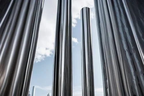 Modern column design, sleek metallic material, silver chrome finish, minimalist ornamentation, slender cylindrical shape, smooth rounded edges, futuristic ambiance, urban cityscape background, daytime