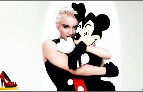 Madonna is on a movie set and she has Mickey Mouse on her shoulders. Madonna is wearing a sexy dress and has beautiful legs and she is wearing high heels. The movie set is full of crew members such as