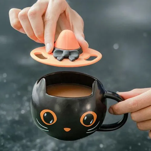 someone holding a black mug with orange eyes and an orange cap,tea infuser,asian teapot,fragrance teapot,halloween coffee,robocup,tea cup fella