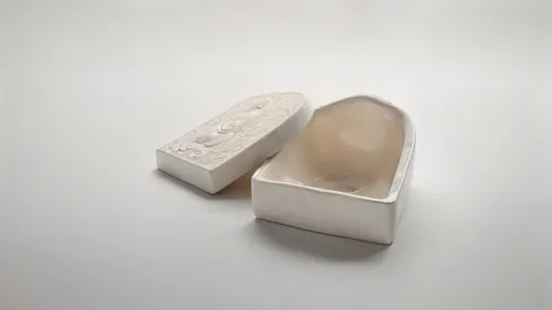 two soaps sitting in a white box,premolar,premolars,clay packaging,coconut oil soap,dreidels,bridal shoes